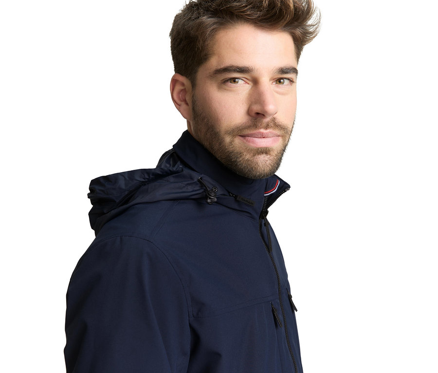 Muž má na sebe bomber bundu Tom Tailor, Sky Captain modrá s kapucňou.
