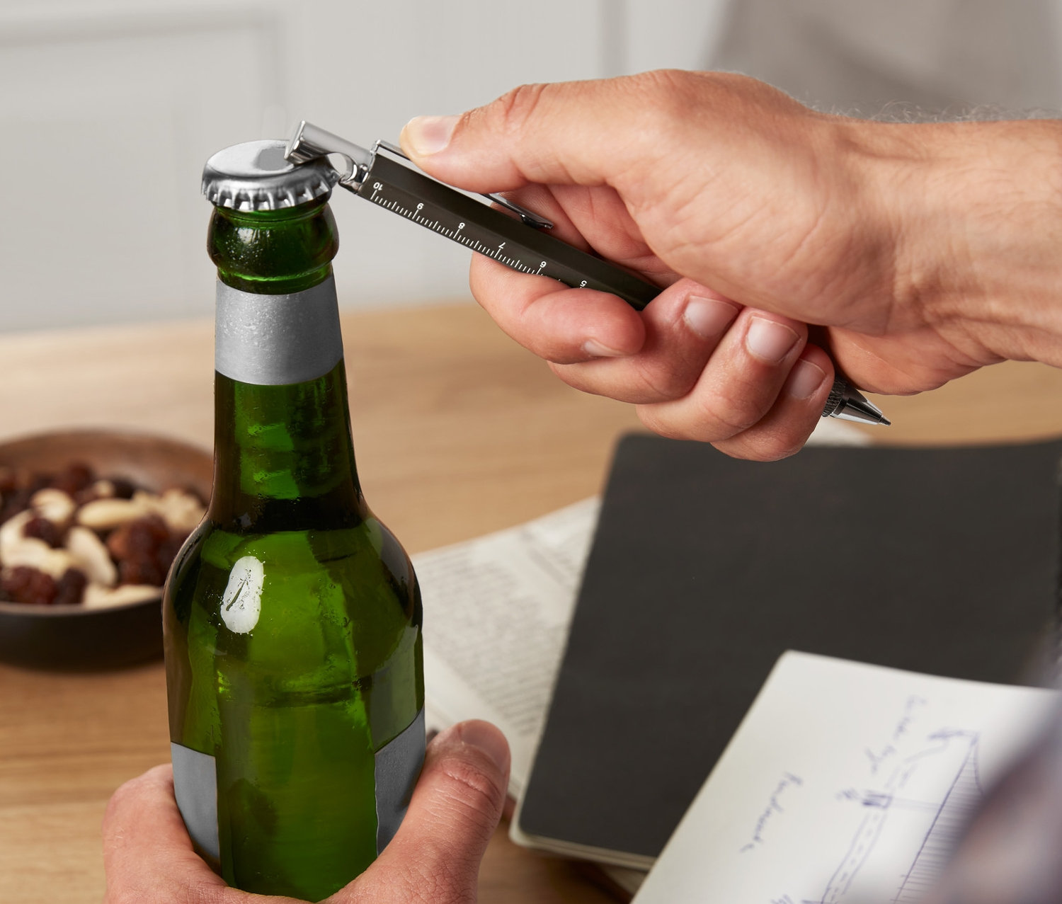 Muž otvára zelenú fľašu multifunkčným perom.