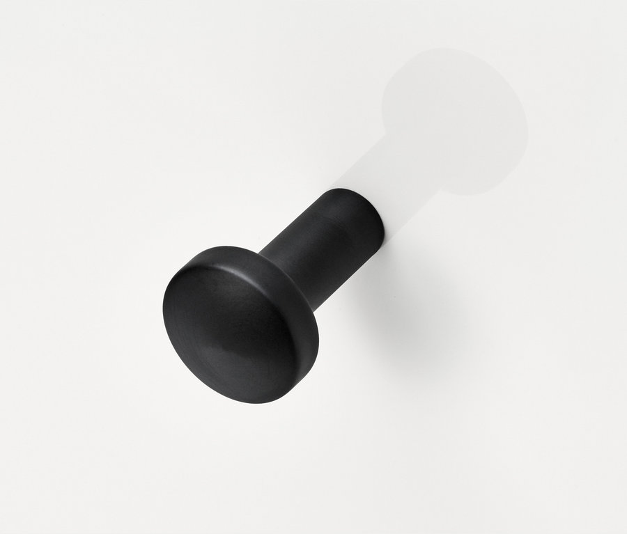 Čierny drevený kolík na bielej stene.