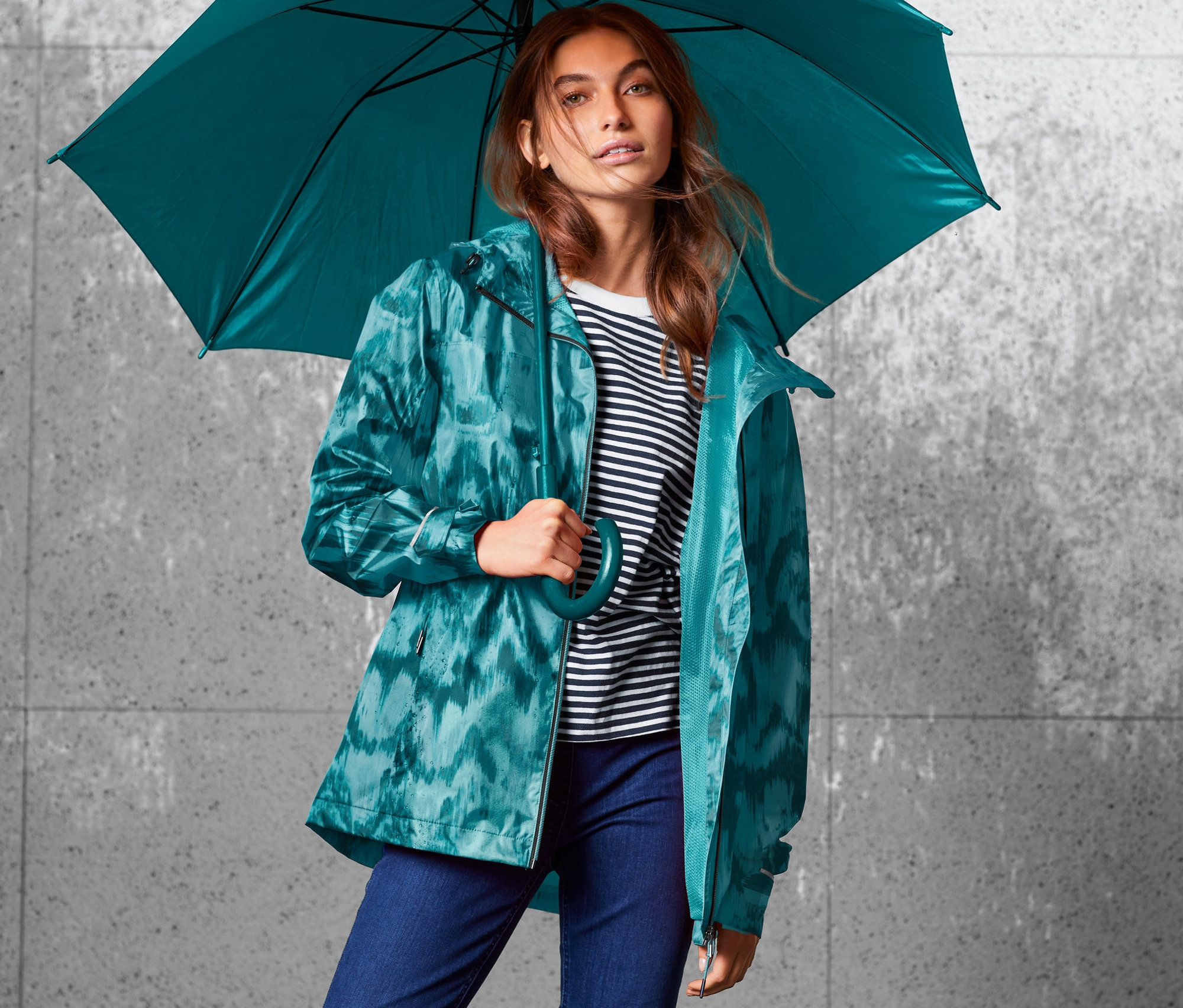 Žena drží dáždnik a má na sebe bundu do dažďa s celoplošnou potlačou.