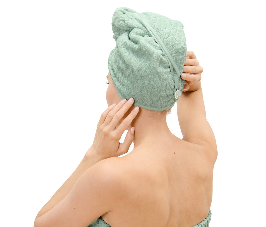 Žena si upravuje uterákový turban na hlave.