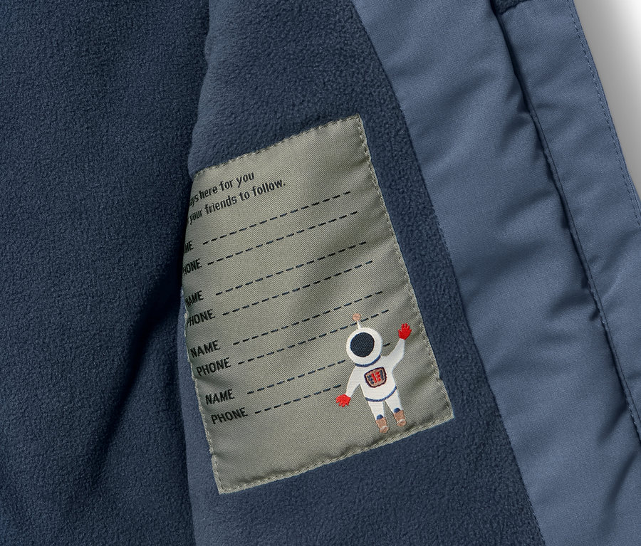 Detail detskej zimnej súpravy s vnútorným vreckom a štítkom na meno.