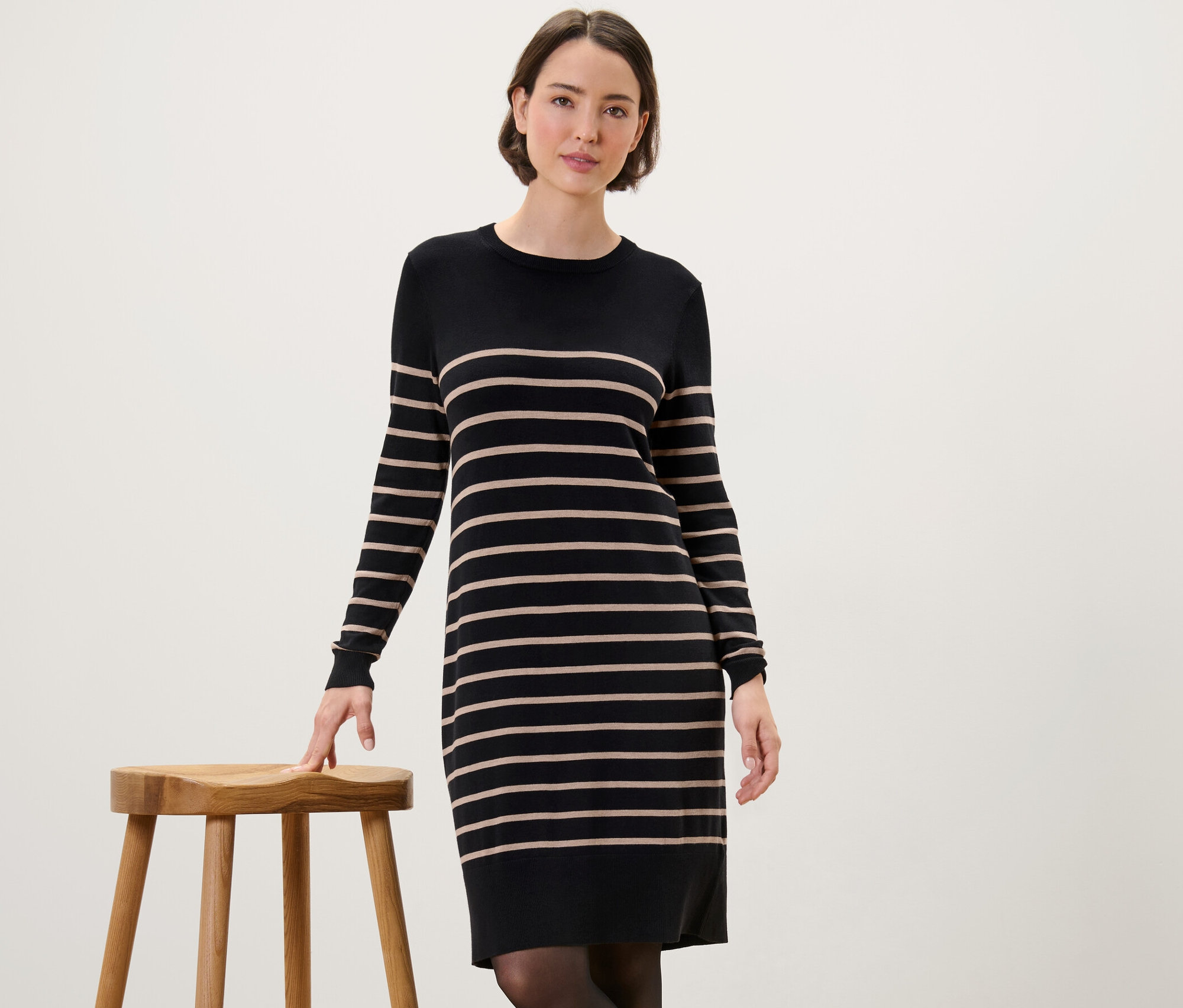 Žena pózuje v prúžkovaných šatách z jemného úpletu.