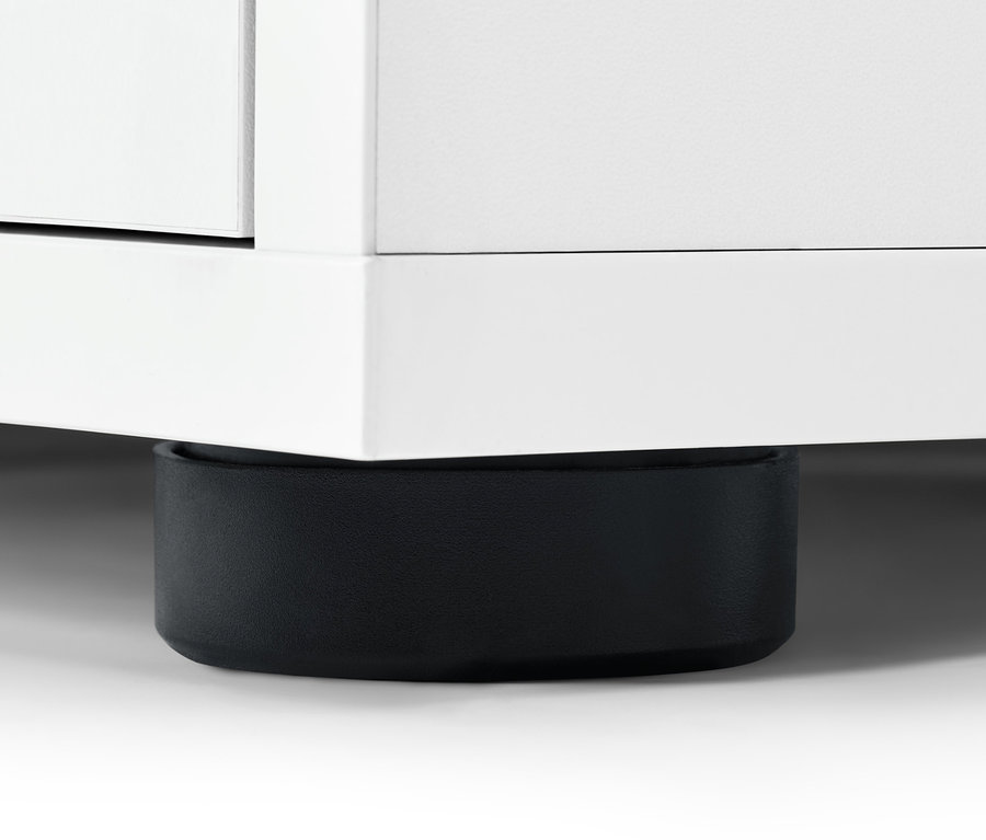 Detail bielej komody so zásuvkami s čiernou nohou.