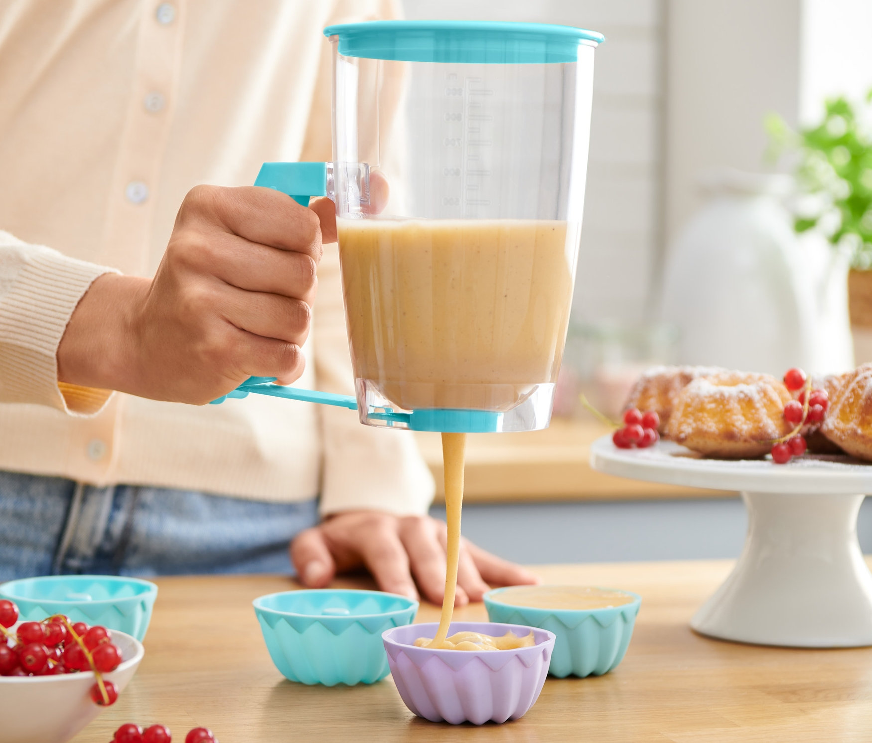 Žena používa dávkovač cesta na plnenie silikónových formičiek na muffiny.