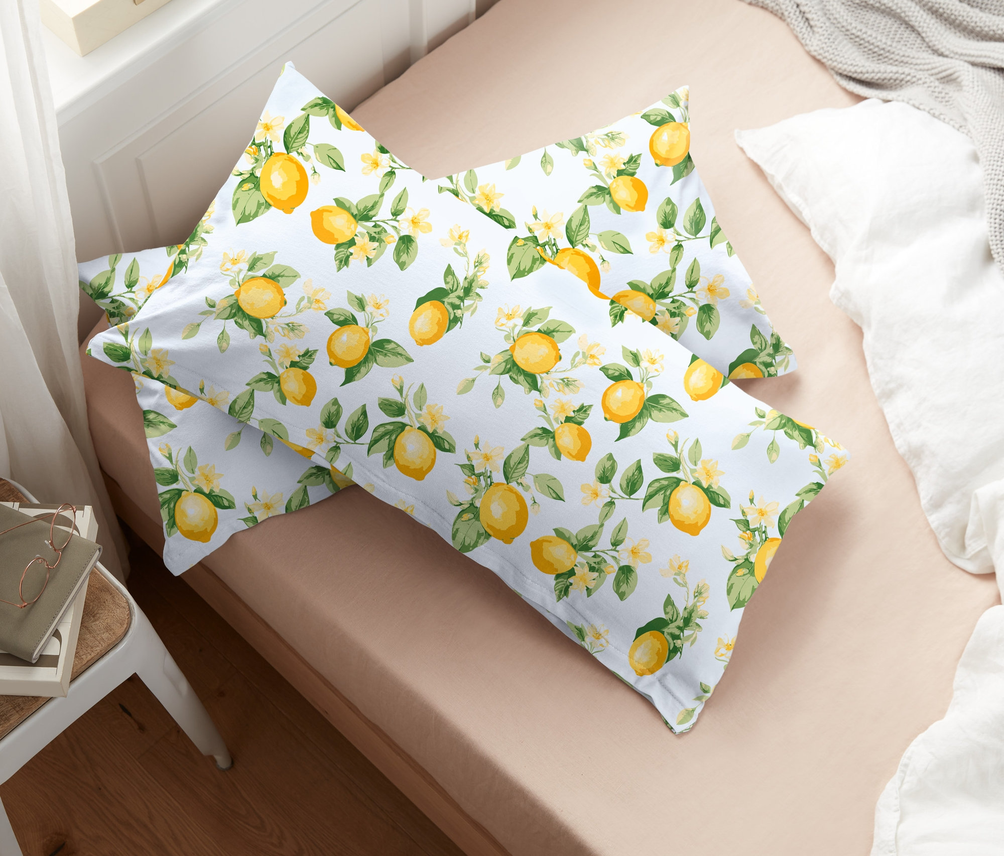 Dve džersejové obliečky na vankúše s potlačou citrónov ležia na posteli.