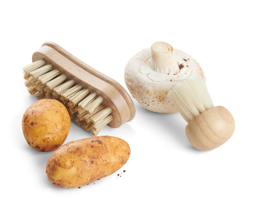 Dve zemiaky a šampiňón vedľa dvoch kefiek na zeleninu.