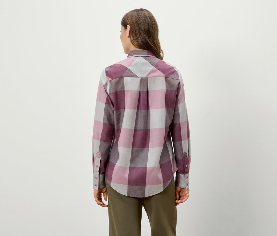 Zozadu je vidieť žena v kockovanej košeli s dlhým rukávom a zelených nohaviciach.