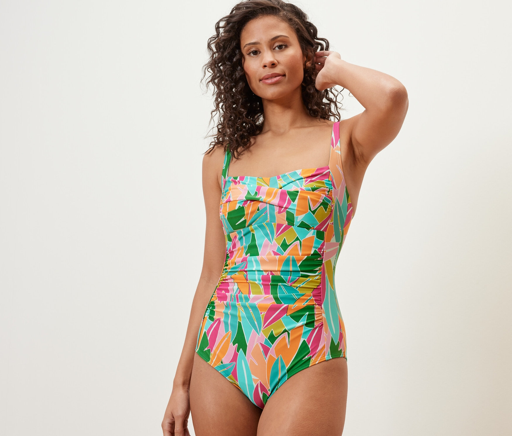 Žena pózuje v jednodielnych plavkách tvarujúcich postavu, viacfarebné.