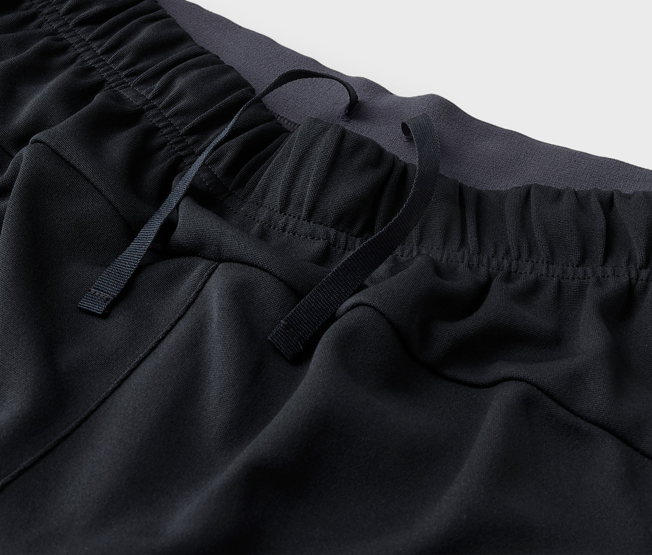 Detail čiernych športových nohavíc so sťahovacou šnúrkou v páse.