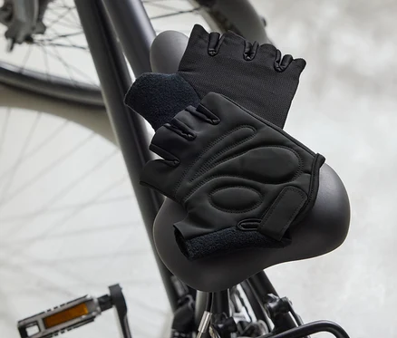 Dve čierne cyklistické rukavice ležia na čiernom sedadle bicykla.