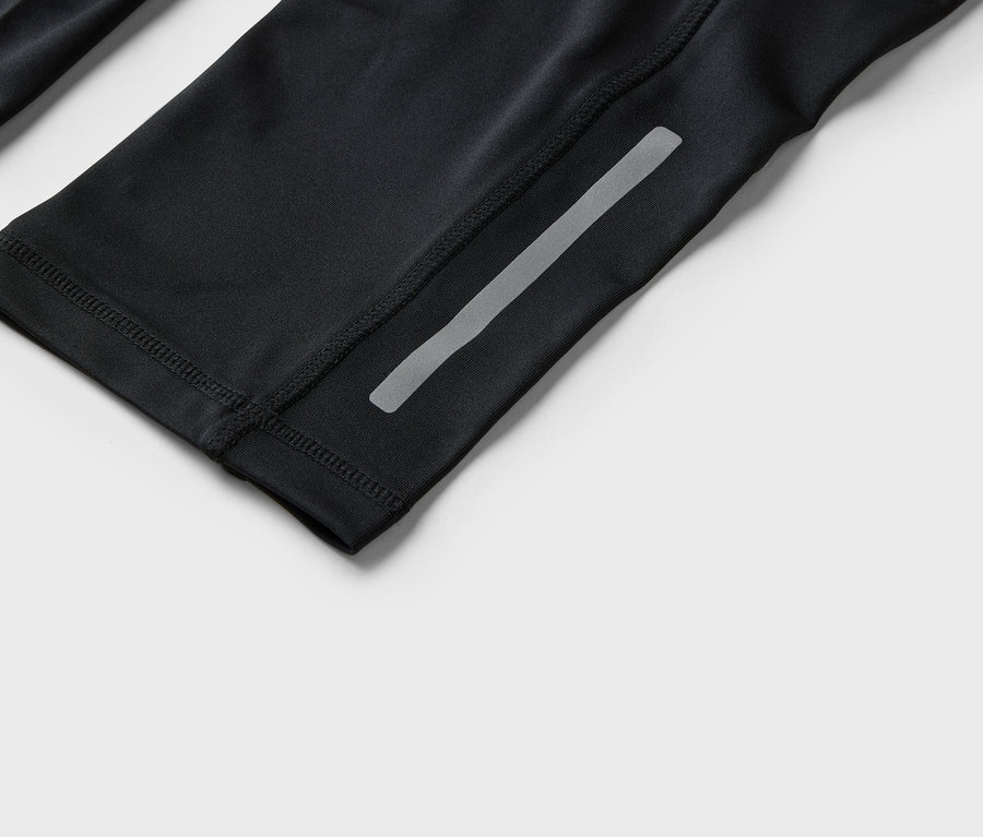 Detailný záber na čierne športové oblečenie s reflexným pásikom.