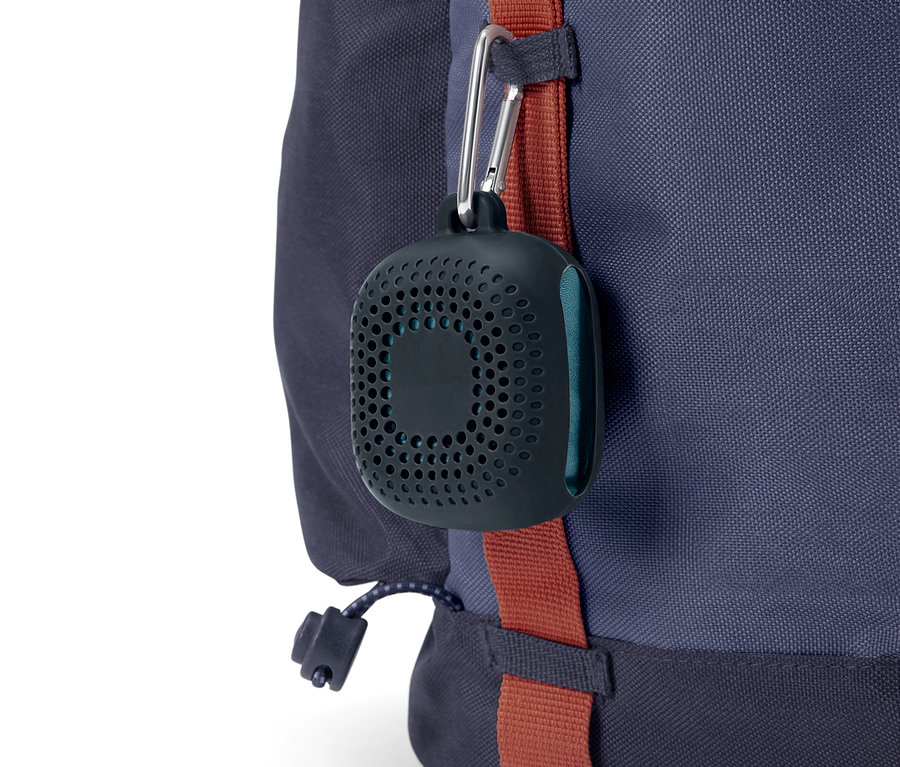 Čierny, okrúhly obal s dierami visí na karabíne z modrého batohu.