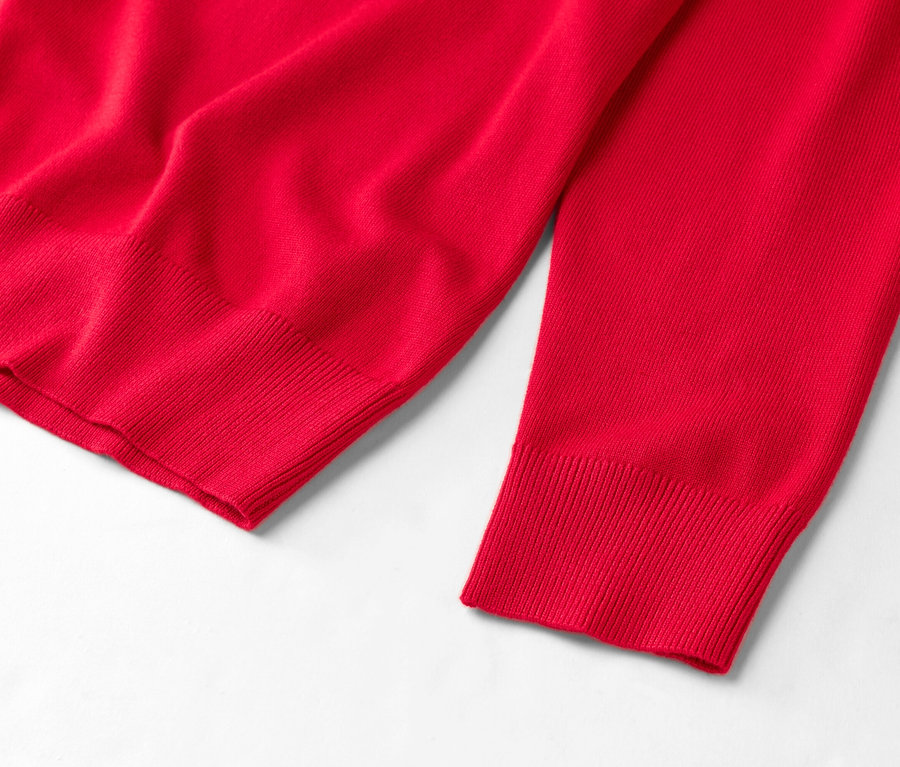 Detailný pohľad na červený sveter na bielom pozadí.