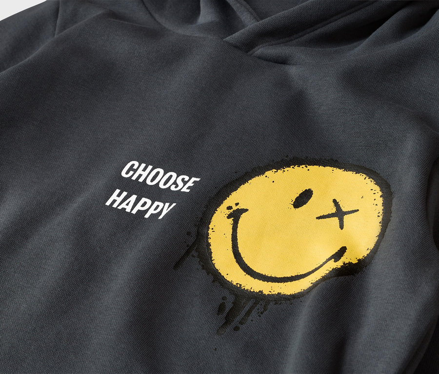 Tmavosivá mikina s kapucňou so žltým smajlíkom a nápisom "CHOOSE HAPPY". Smajlík má jedno oko ako bodku a druhé ako krížik, pôsobí ako nastriekaný.