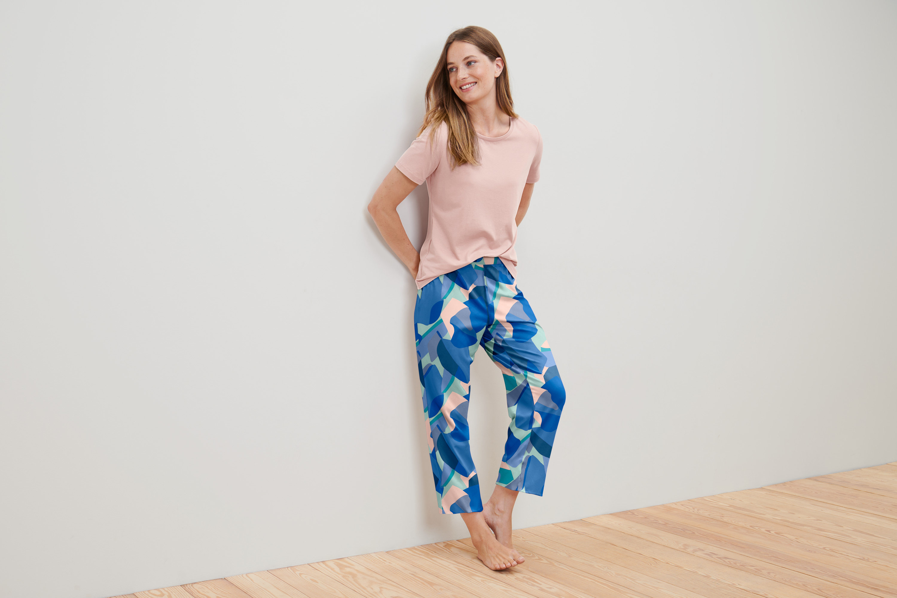 Žena v pyžame sa opiera o stenu.