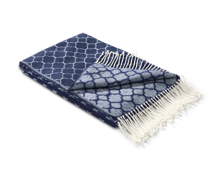 Modrý žakárový pléd s bielymi strapcami, čiastočne zložený.