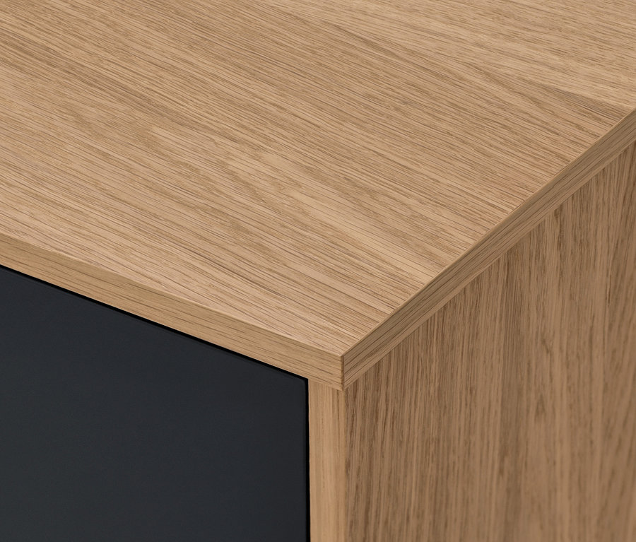 Detail rohu komody Bekeson v antracitovej farbe s drevenou doskou.