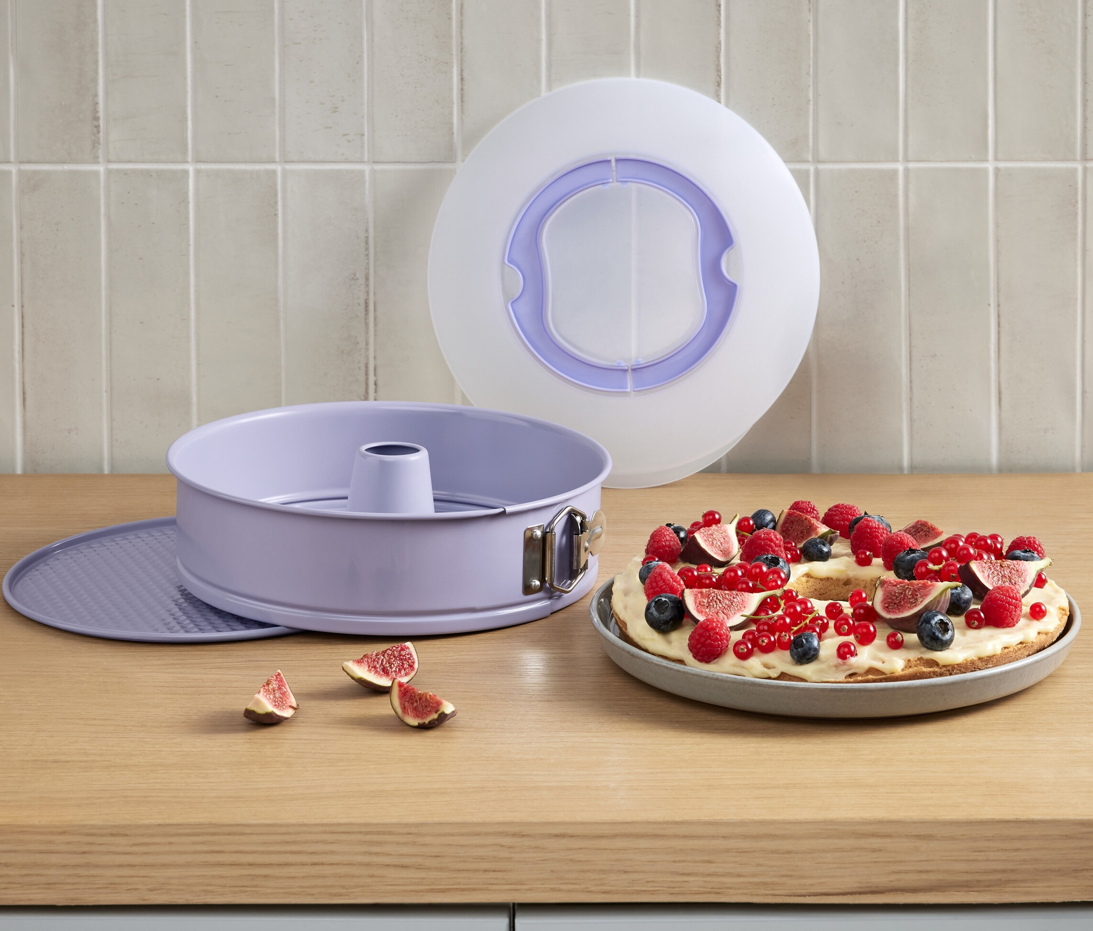 Fialová tortová forma s vekom vedľa torty s ovocím.