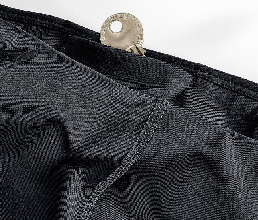 Detail čiernych trojštvrťových športových legín s kľúčom vo vrecku.