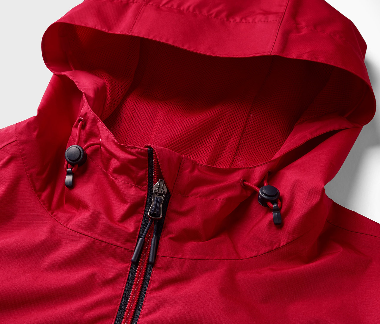 Detail červenej bundy do dažďa so zipsom a kapucňou.
