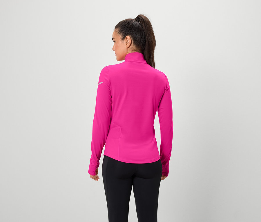 Žena chrbtom k fotoaparátu má na sebe ružový top s dlhým rukávom a čierne legíny.