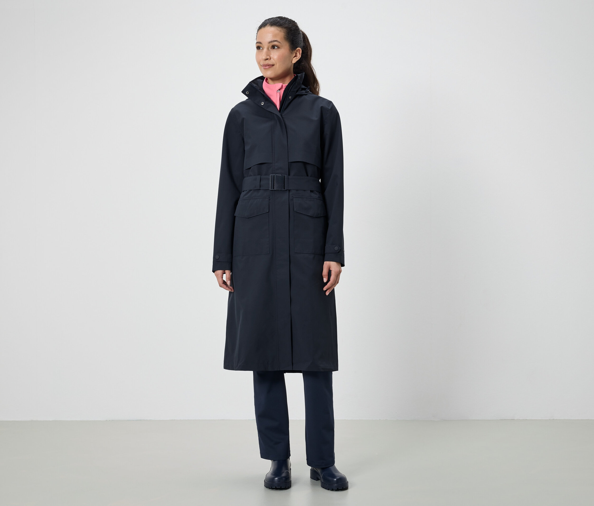 Žena má na sebe dlhý čierny kabát s opaskom.