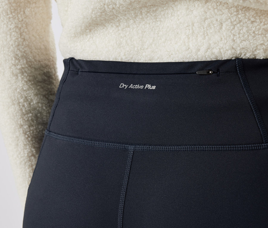 Detail dámskych čiernych legín s nápisom "Dry Active Plus" a vreckom na zips v hornej časti.
