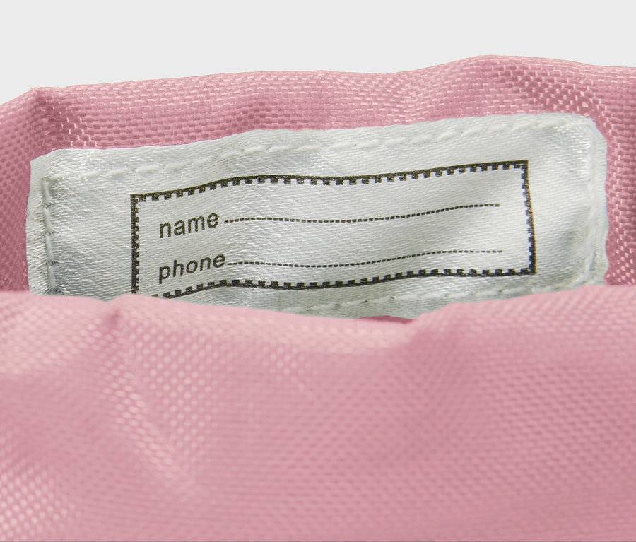 Detail detských gumákov s celoplošnou potlačou kvetov, zobrazujúci štítok na meno.