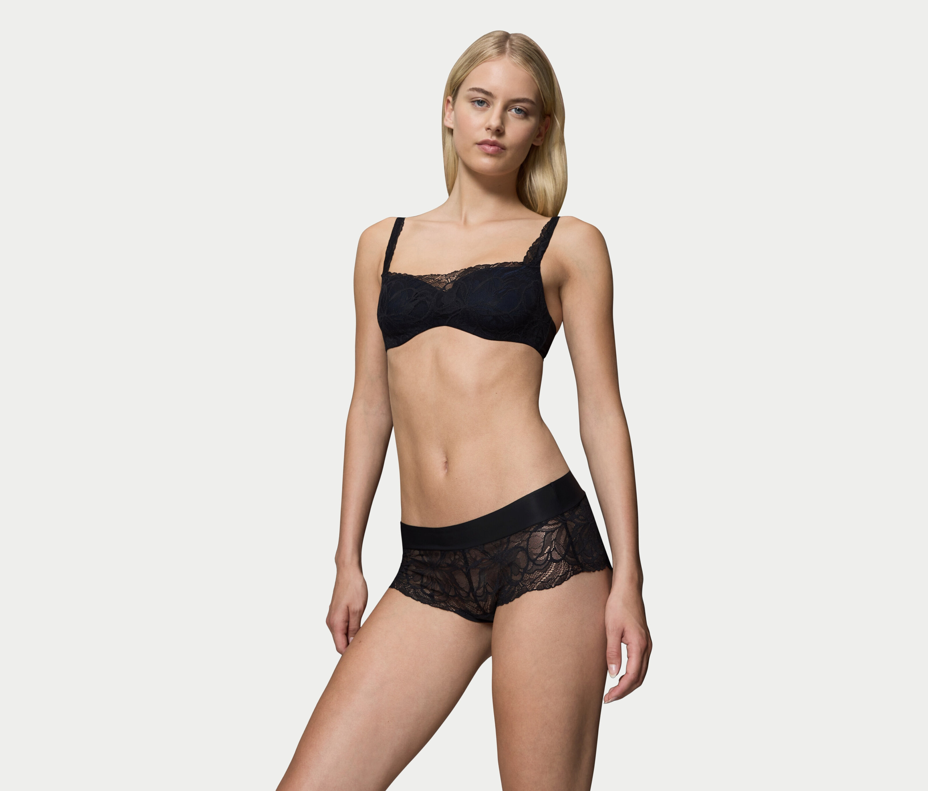 Blondína pózuje v čiernej čipkovanej podprsenke a nohavičkách.
