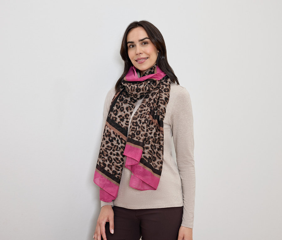 Žena s tmavými vlasmi pózuje s leopardím šálom s ružovými akcentmi.