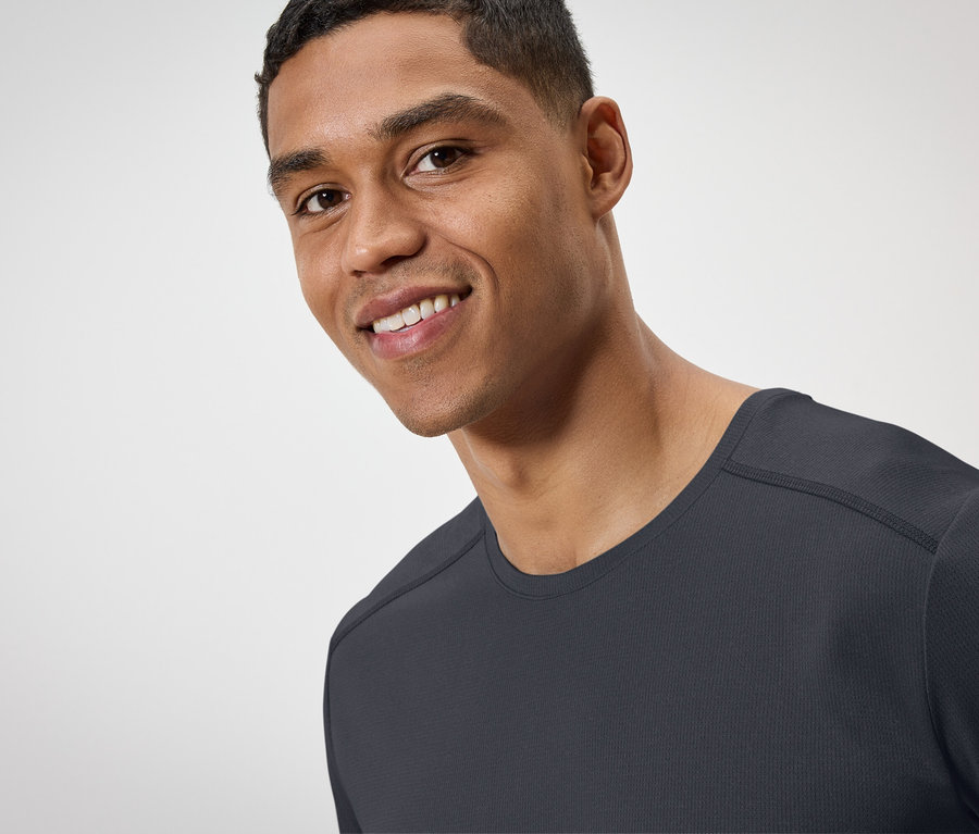 Portrét usmievajúceho sa muža v čiernom tričku.