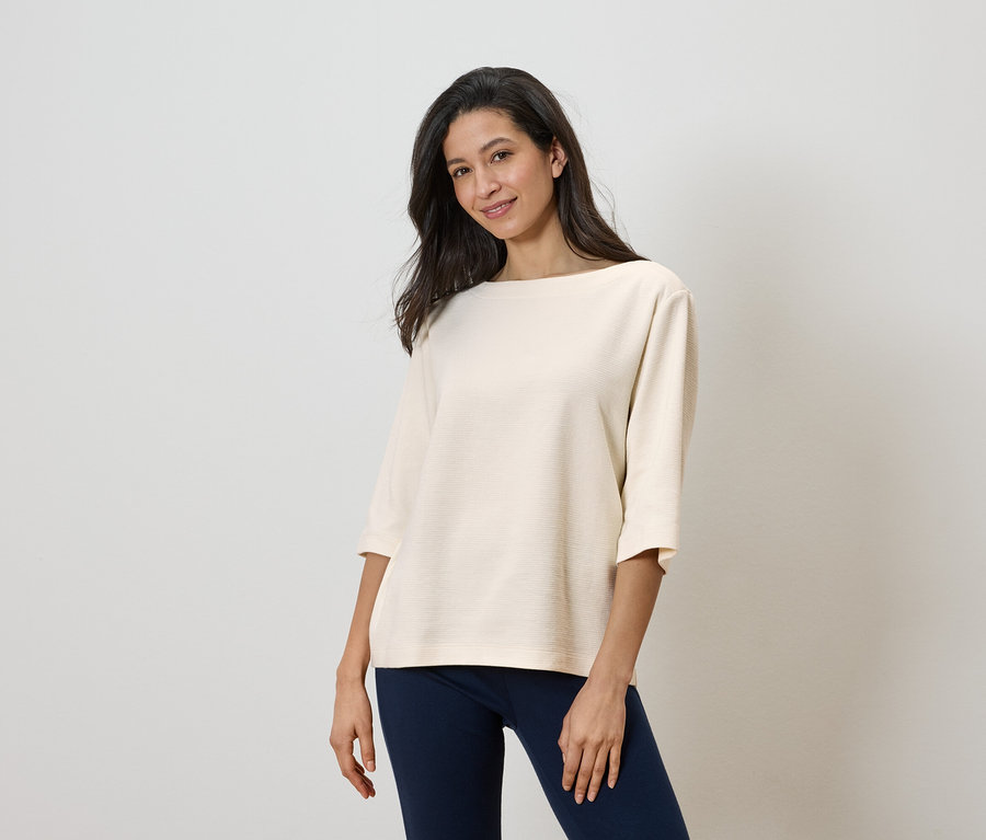 Žena má na sebe svetlý top a tmavé nohavice.