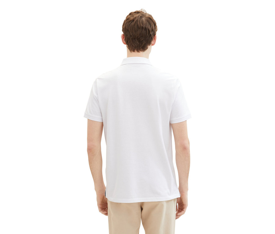 Muž zozadu v bielom piké polokošeli Tom Tailor a béžových nohaviciach.