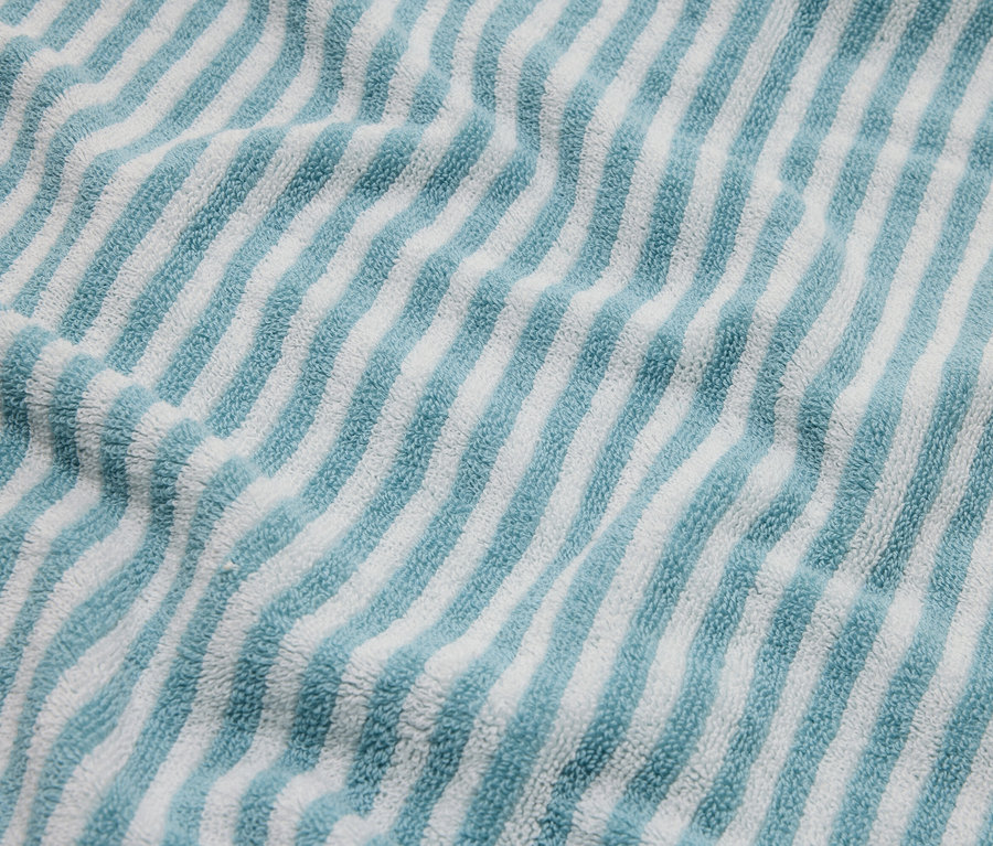 Detailný záber na modro-biely pruhovaný froté uterák.