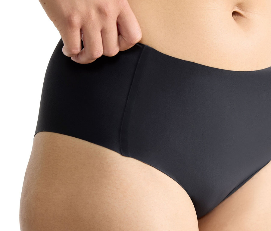 Detail trupu osoby v čiernych nohavičkách sloggi ZERO Feel 2.0 High Waist. Ruka jemne ťahá pás nohavičiek na ľavej strane.