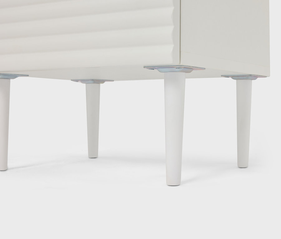 Detailný pohľad na bielu skrinku so štyrmi kužeľovými nohami.