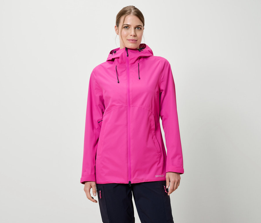 Žena má na sebe ružovú bundu do dažďa s kapucňou a tmavomodré nohavice na bielom pozadí.