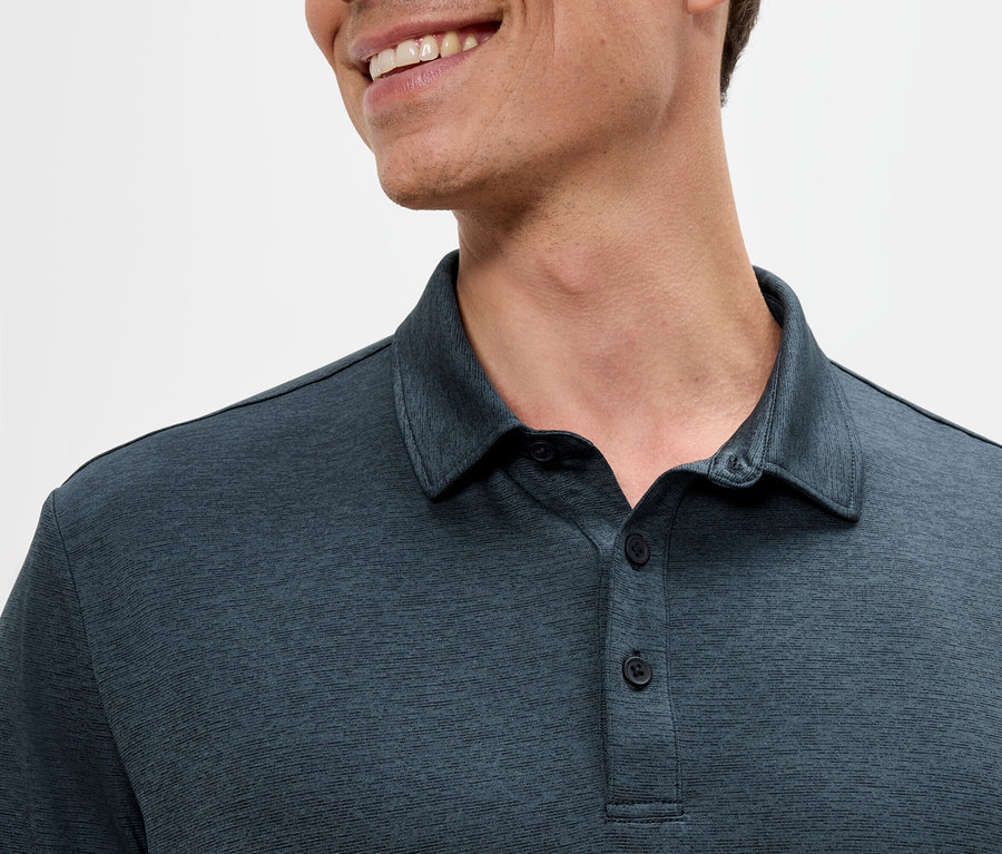 Detail muža v tmavomodrej polokošeli, ktorý sa usmieva.