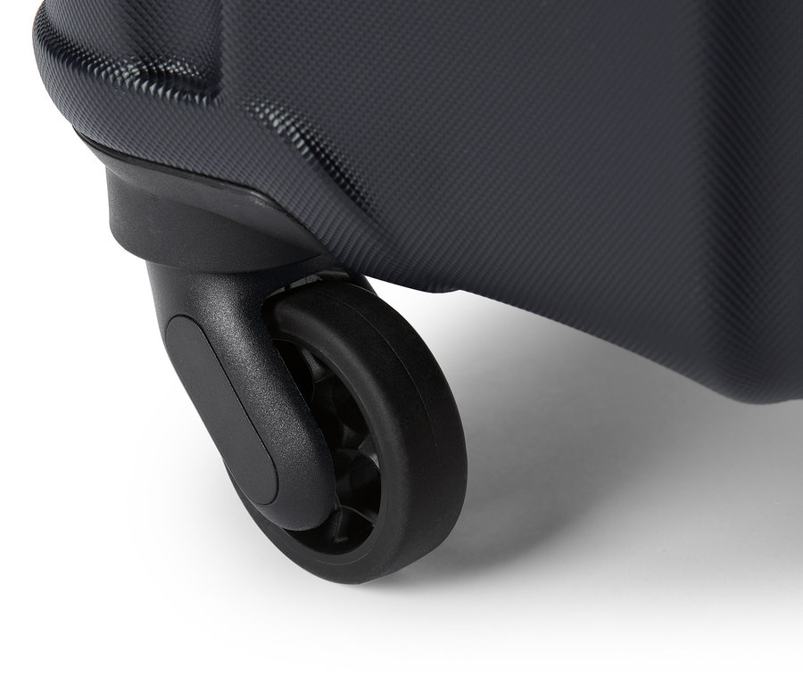 Detailný záber na čierne koliesko kufra na bielom pozadí.