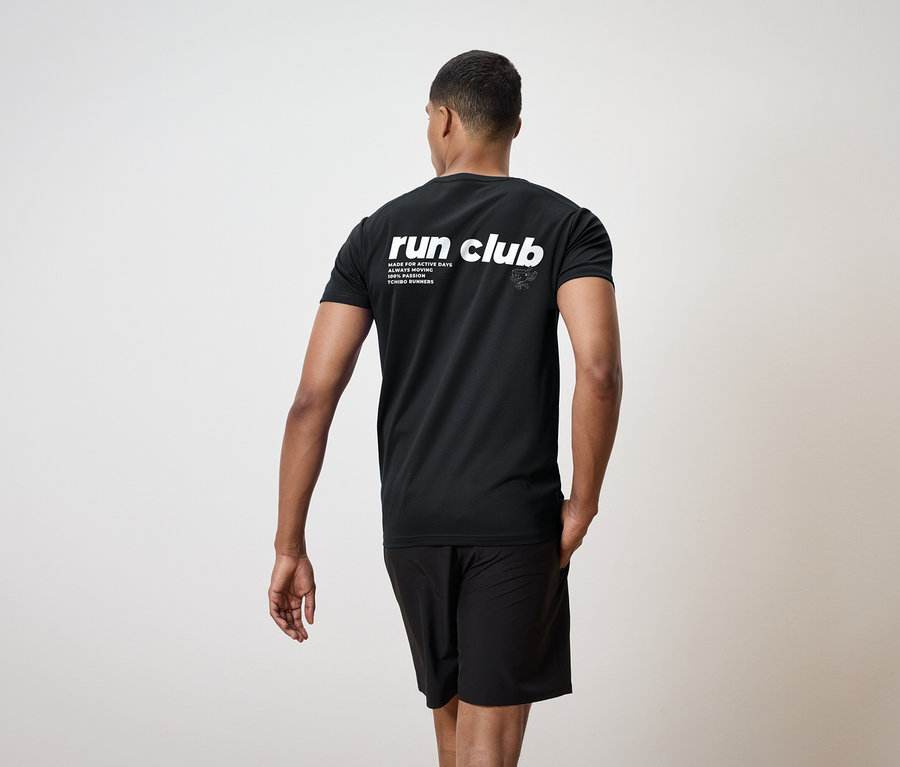 Muž zozadu, oblečený v čiernom tričku s nápisom "run club" a čiernych šortkách.