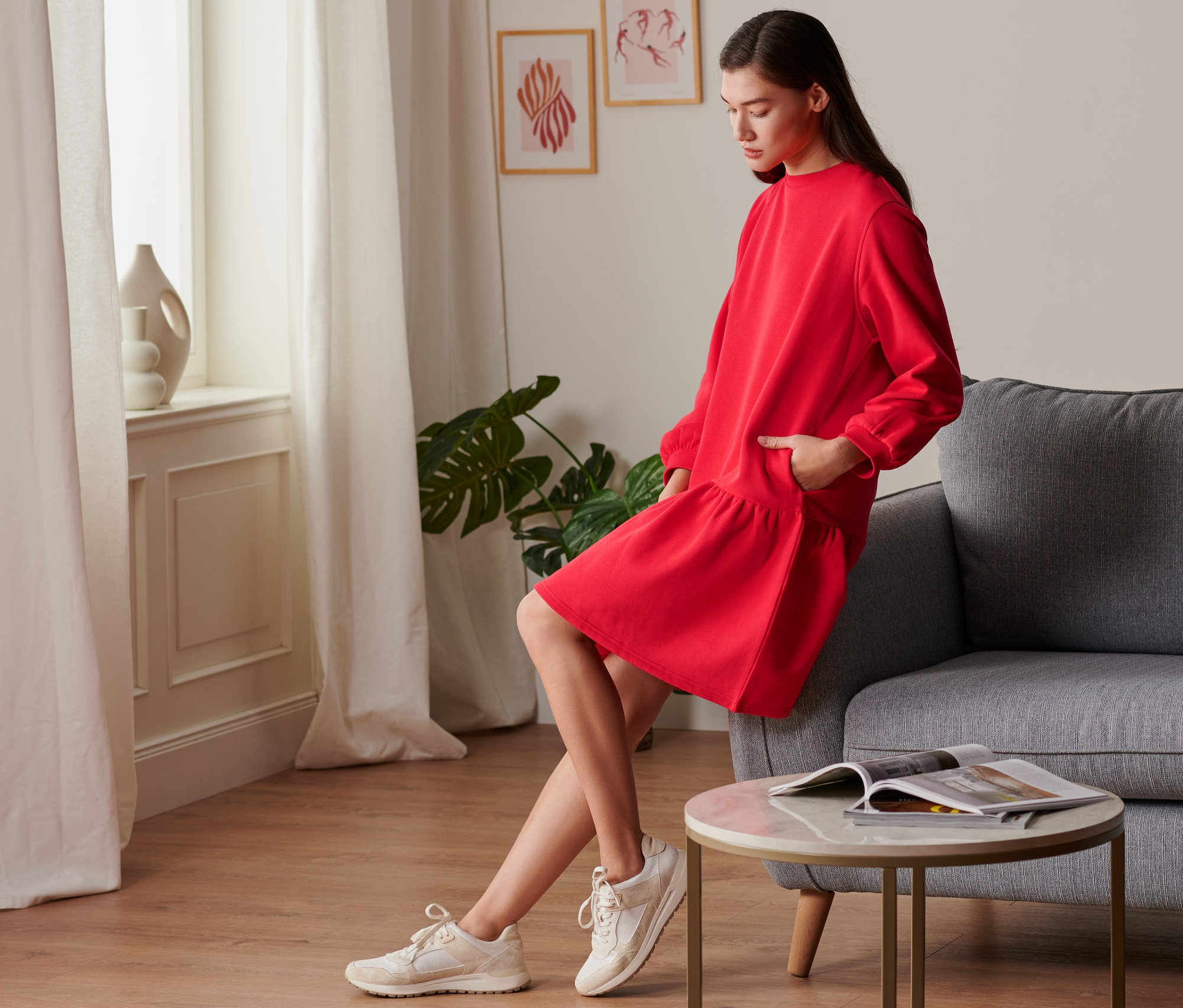 Žena pózuje v červených teplákových šatách.