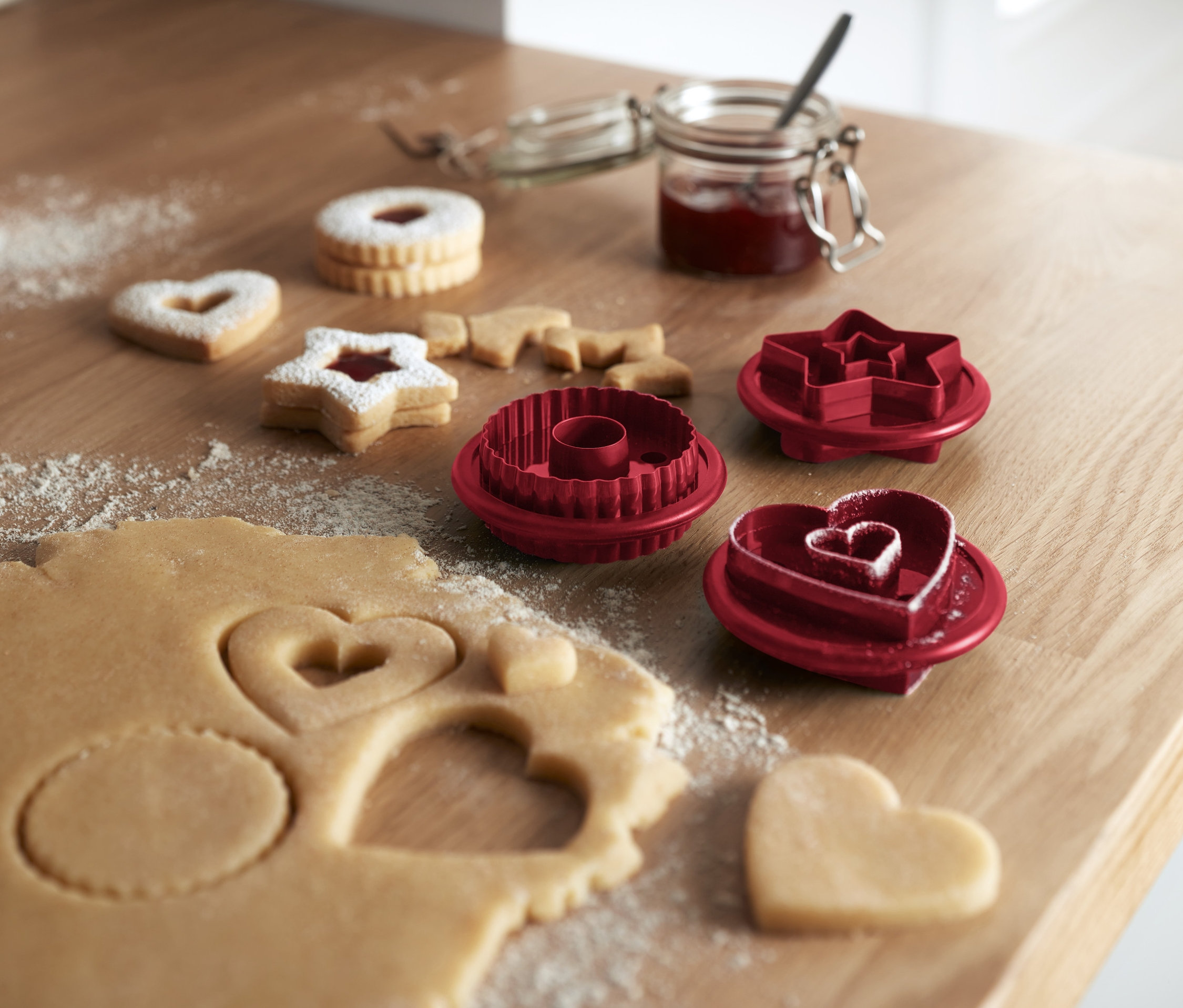 Cesto s formičkami na vykrajovanie lineckých koláčikov a upečené koláčiky na drevenom stole.