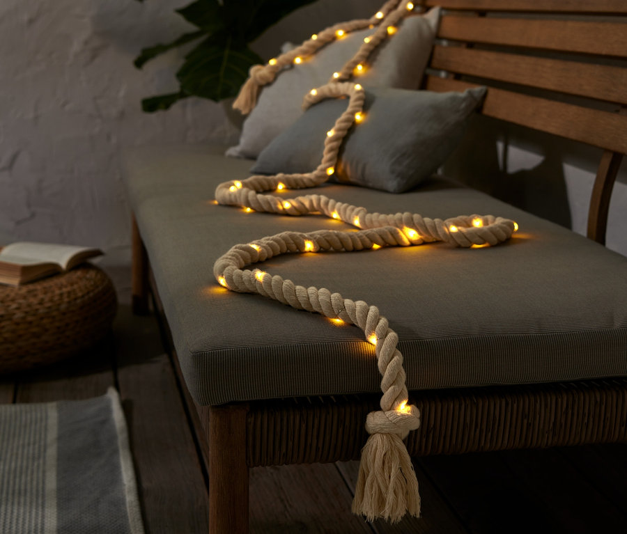 Svetelná reťaz s LED Lano leží na lavici s vankúšmi.