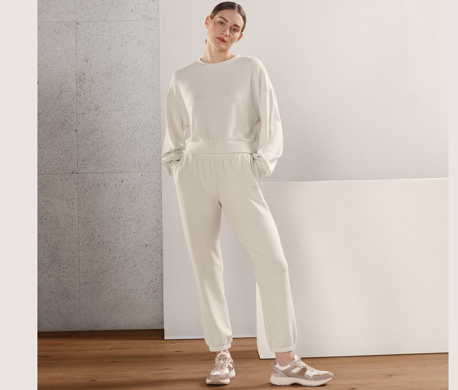 Žena pózuje v obzvlášť mäkkej mikine a teplákových nohaviciach.