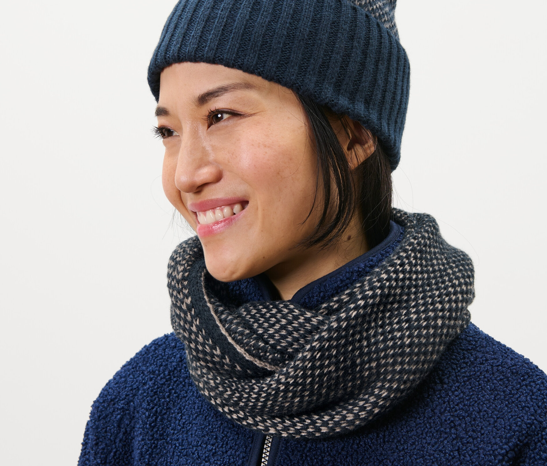 Žena má na sebe pletený kruhový šál a čiapku.