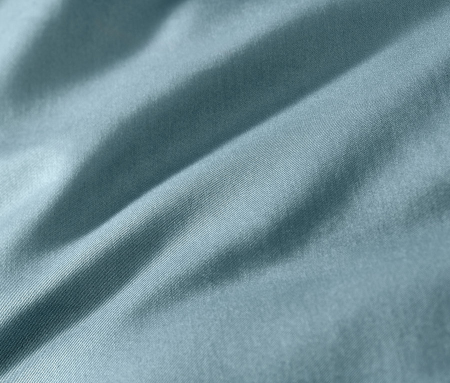 Detailný záber na modrú posteľnú bielizeň z bavlny a saténu.