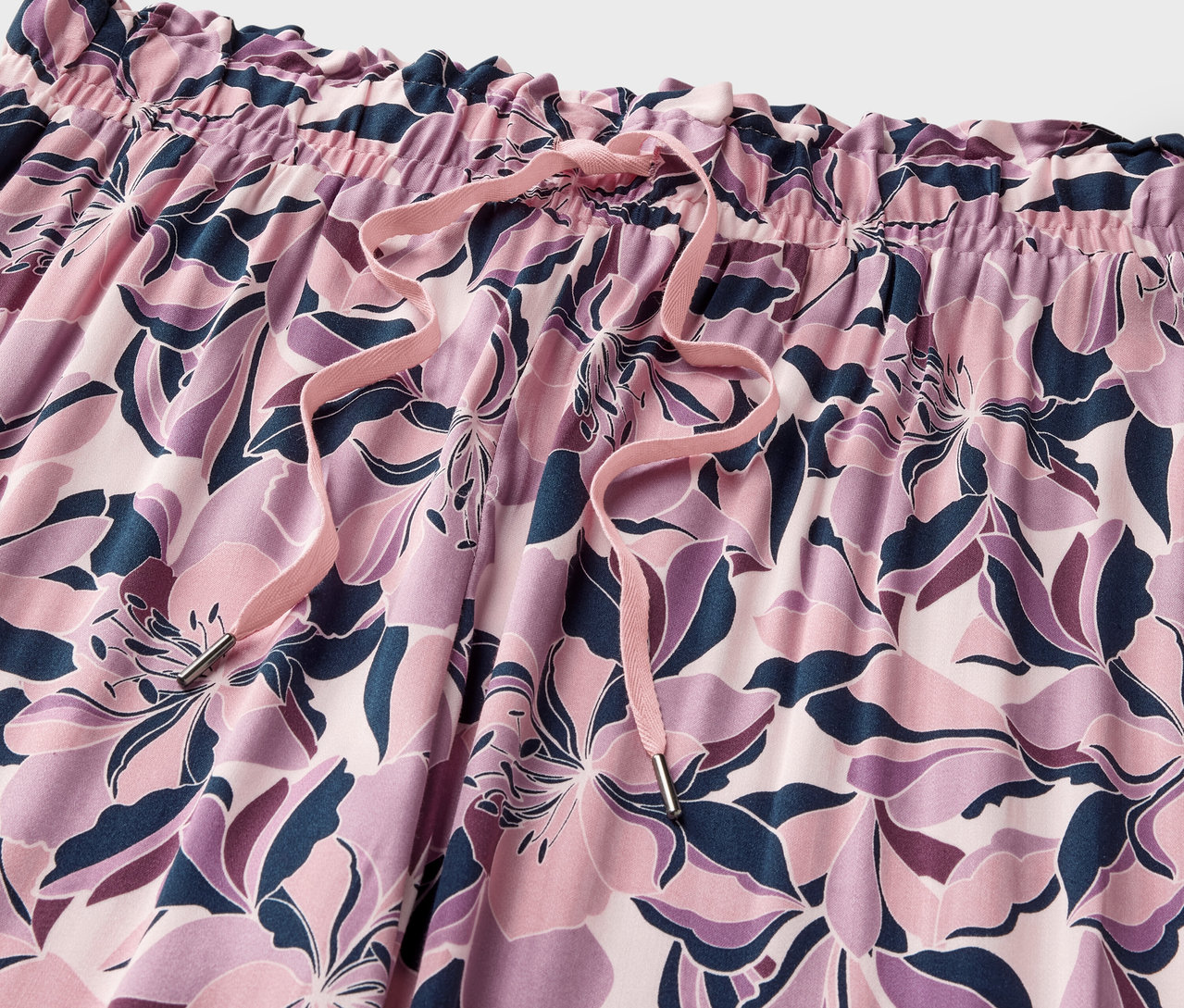 Detailný záber na pohodlné nohavice s kvetinovou potlačou a šnúrkou.