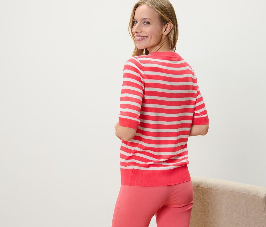 Žena sa pozerá cez plece a má na sebe pruhovaný pulóver z jemného úpletu.