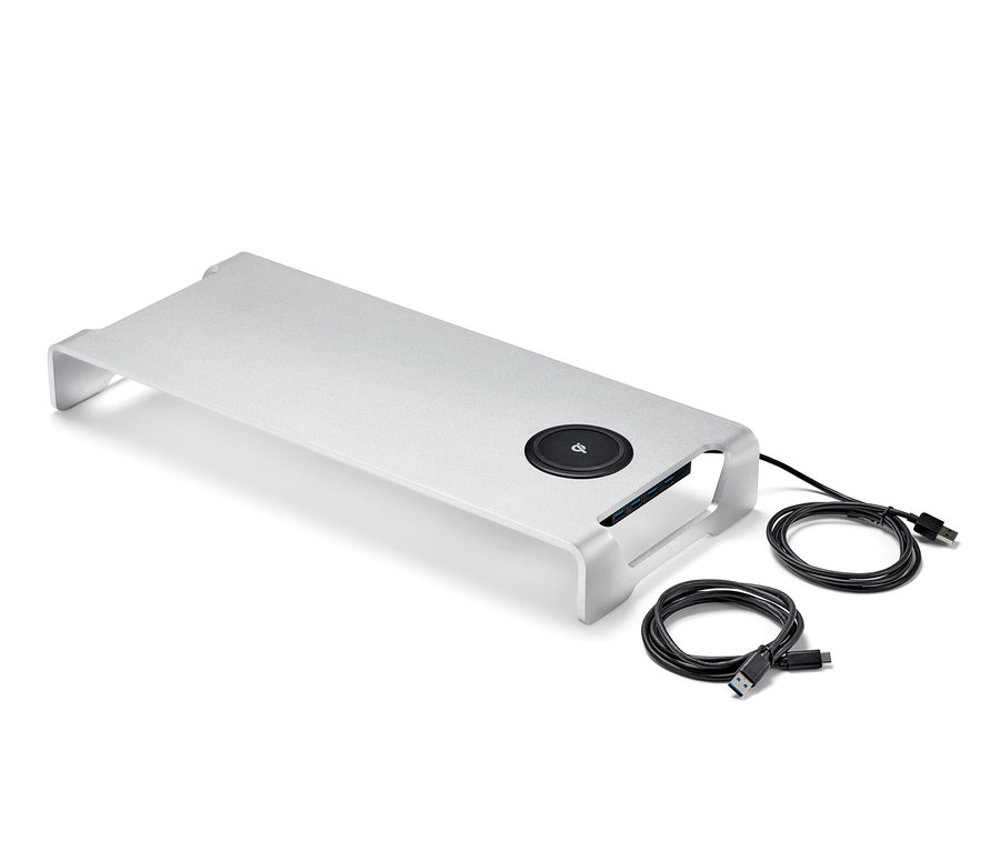 Strieborný stojan na monitor s bezdrôtovou nabíjacou stanicou a USB hubom a dva čierne káble na bielom pozadí.